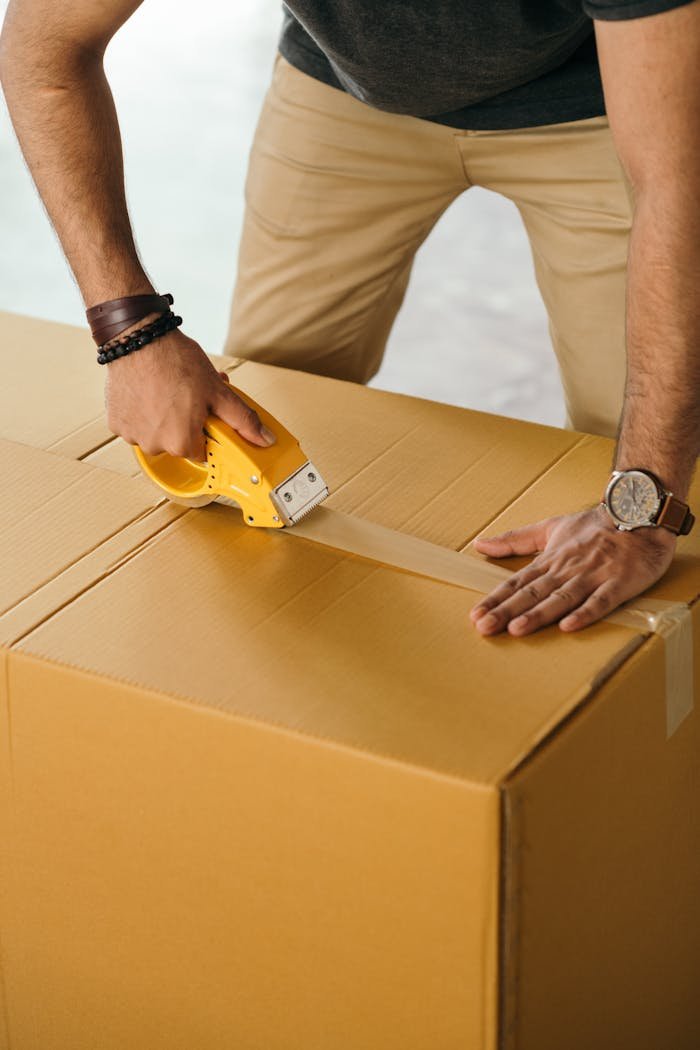 team-01 Unrecognizable man sealing box with duck tape while preparing for moving out